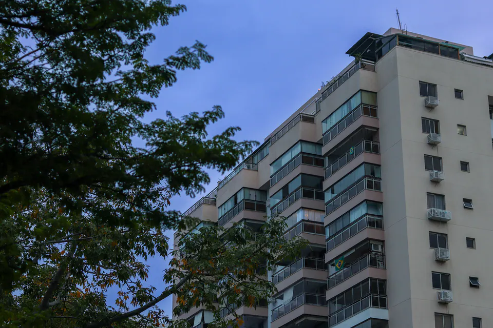 prédio residencial visto de baixo, entre árvores e céu azul