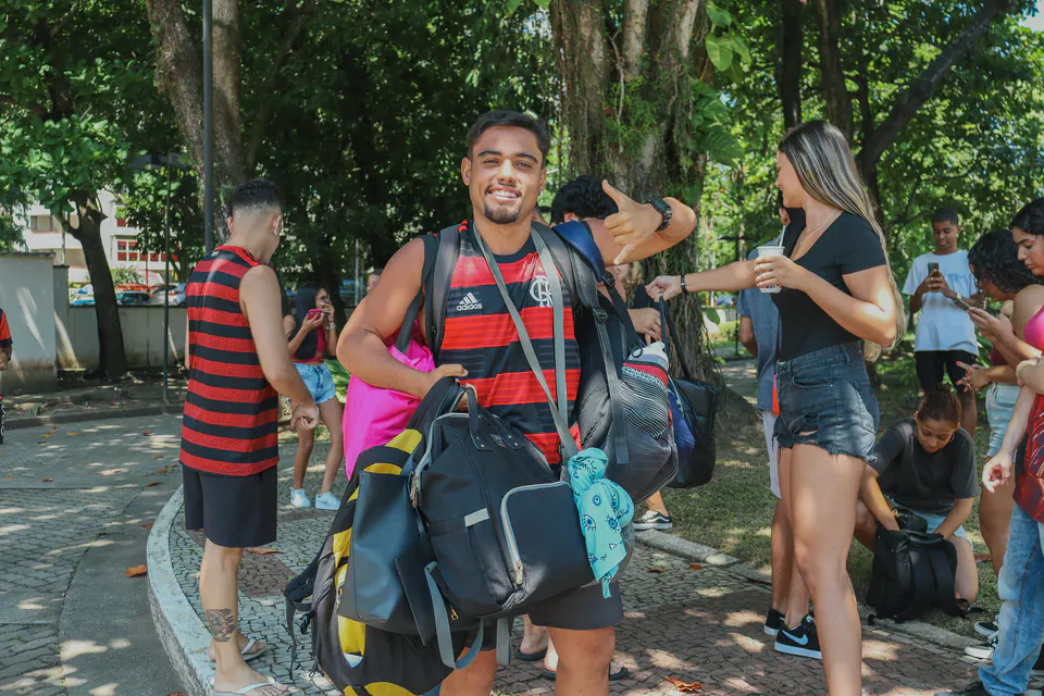 calouro chega carregando mochilas e sorri para a câmera